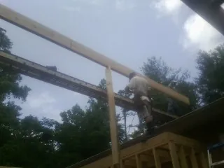 Carpenter setting a ridge beam over a new addition frame — Ice Dam Removal by Roofing Brothers in Cumbola