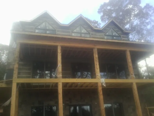 Dormers and porch framing on a large log home under construction — Roof Coating work by our crew in Cumbola