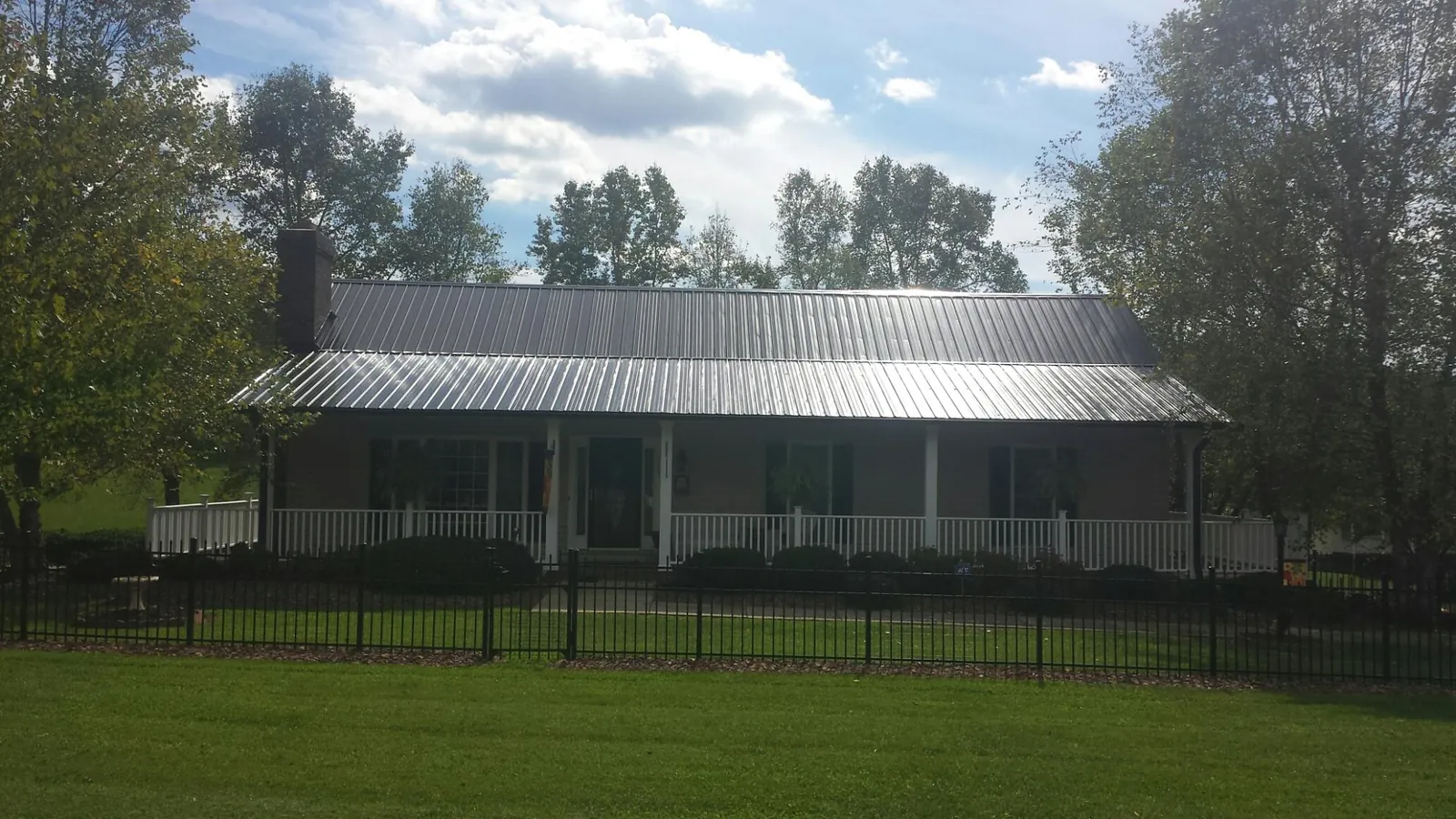 Gray metal roof on a brick ranch with a full width front porch — Gutter Guard Installation work by our crew in Cumbola